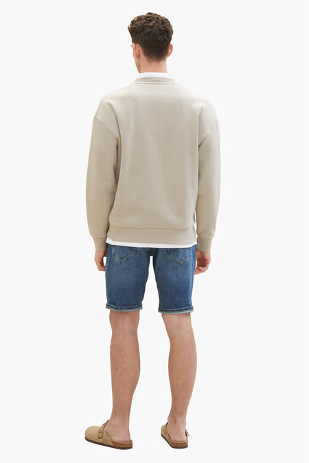 Jean short bleu marine de TOM TAILOR, vu de l'arrière, associé à un pull beige et des sandales brunes.
