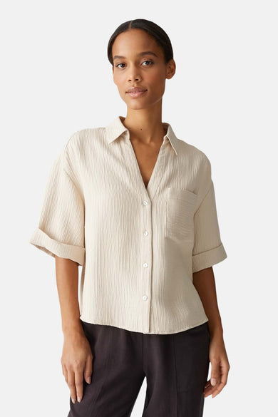 Chemise beige à manches courtes d'OPUS, avec un effet froncé et portée avec un pantalon foncé.