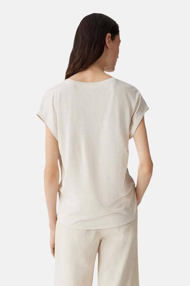 Blouse bleue claire sans manches d'OPUS, vue de derrière et associée à un pantalon beige.