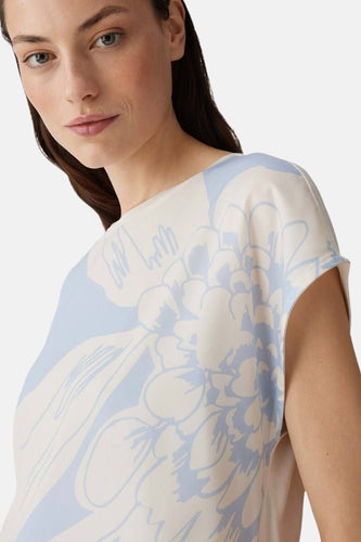 Vrouw in bloemige top, beige en blauw.