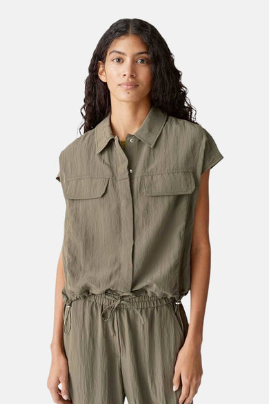 Een vrouw in een kaki jumpsuit met korte mouwen.