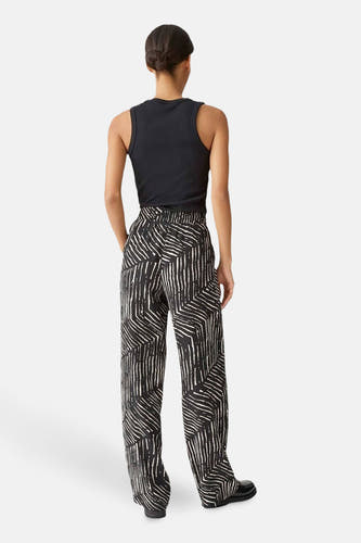 Pantalon noir OPUS avec un motif blanc abstrait, vu de derrière avec un haut noir.