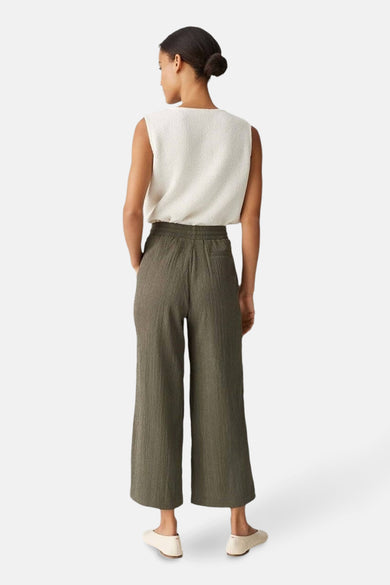 Pantalon kaki d'OPUS, avec une texture tissée, des jambes larges et associé à une chemise blanche.