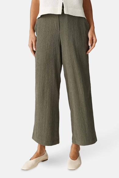 Pantalon kaki d'OPUS, avec une texture pliée et associé à des ballerines beige et un t-shirt tricoté.