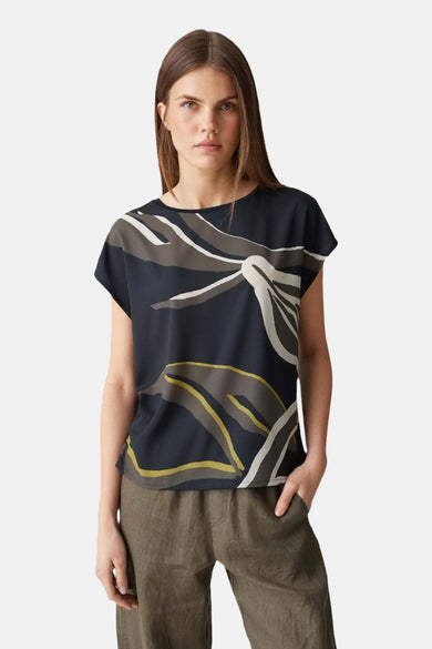 Blouse bleue à manches courtes d'OPUS, avec un motif abstrait de feuilles en blanc, gris et ocre.
