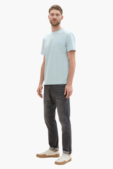 Groen T-shirt met korte mouwen van TOM TAILOR, met borstzak, gecombineerd met donkere jeans en crèmekleurige sneakers.