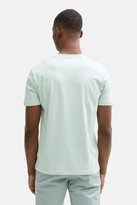 T-shirt vert de mantes courtes TOM TOM TOR, vu vu de dos, porté avec un pantalon gris clair.