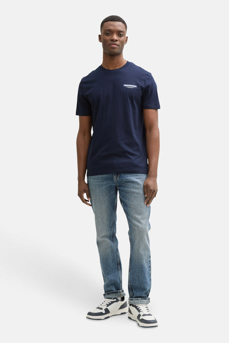 T-shirt bleu à manches courtes de TOM TAILOR, avec une petite impression textuelle, associé à des jeans bleus et des baskets blanches.