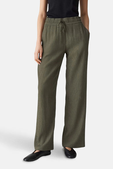 Groene broek van OPUS, met trekkoord in de taille en steekzakken, gedragen met zwarte schoenen.
