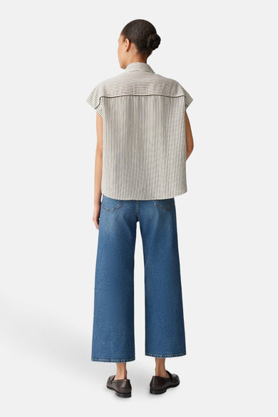 Chemise écru à manches courtes d'OPUS, avec un fin motif rayé, associée à des jeans larges et des loafers.