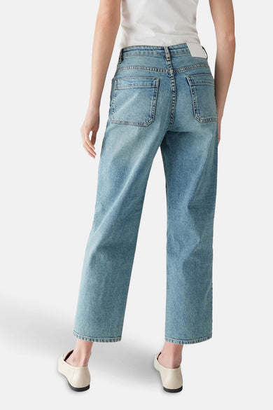 Jean denim bleu clair mom de OPUS, vu de derrière, avec des poches et des chaussures écru.