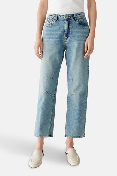 Jean mom en denim bleu clair d'OPUS, avec des surées décoratives sur les genoux et des loafers beige.