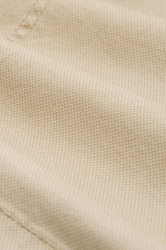 Beige geweven textiel met een subtiel patroon.