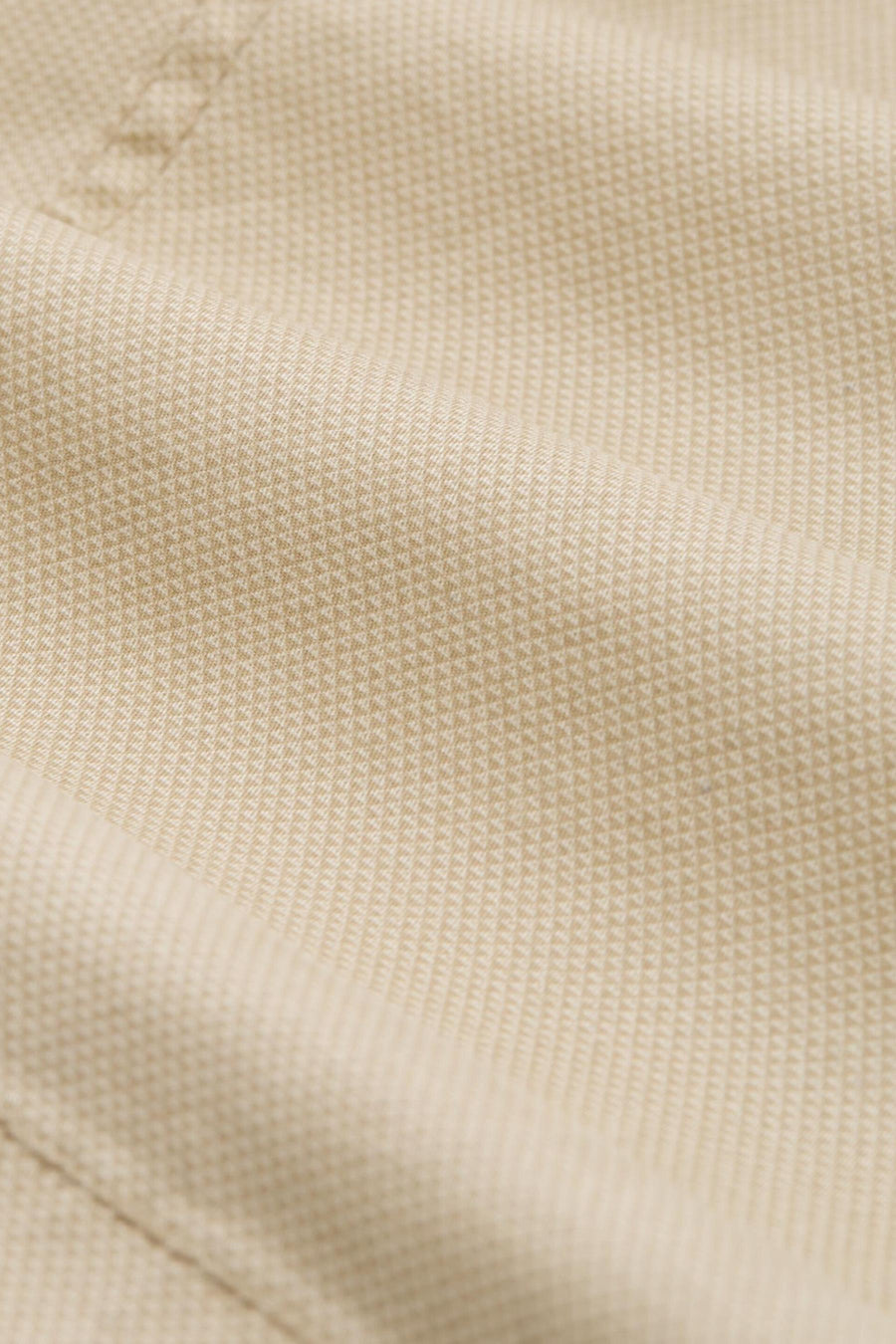 Beige geweven textiel met een subtiel patroon.