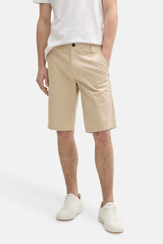 Man met beige shorts en witte sneakers.