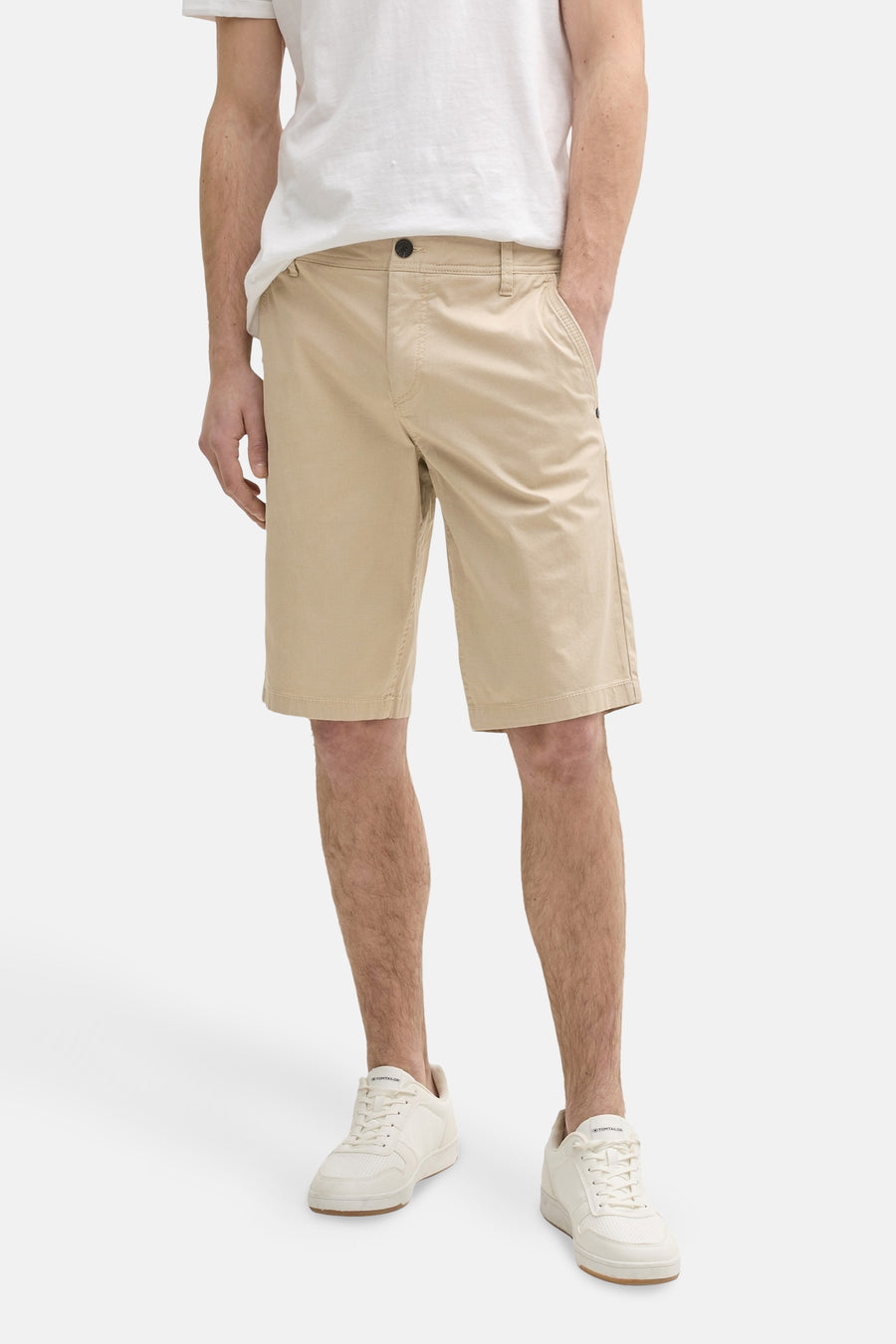 Man met beige shorts en witte sneakers.