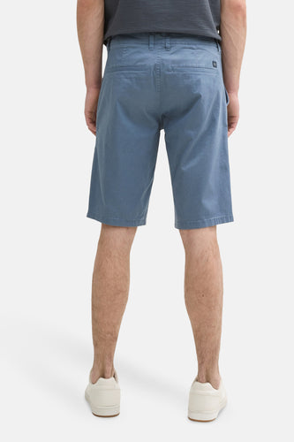 Achterkant van een man in blauwe shorts en witte sneakers.