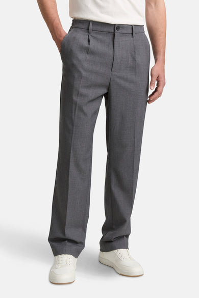Pantalon gris de TOM TAILOR, avec plis et poches, porté avec des baskets blanches.