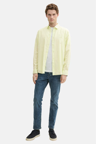 Groen hemd met lange mouwen van TOM TAILOR, gedragen over een wit T-shirt en blauwe jeans, met donkere schoenen.
