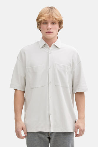 Chemise grise à manches courtes de TOM TAILOR, portée avec un t-shirt blanc, un jean gris et des baskets blanches.