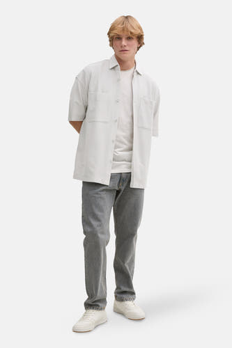 Grijs hemd met korte mouwen van TOM TAILOR, gedragen met een wit T-shirt, een grijze jeans en witte sneakers.
