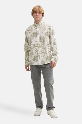 Chemise verte à manches longues de TOM TAILOR, avec un imprimé feuilles de palmier, associée à un jeans gris et des baskets blanches.