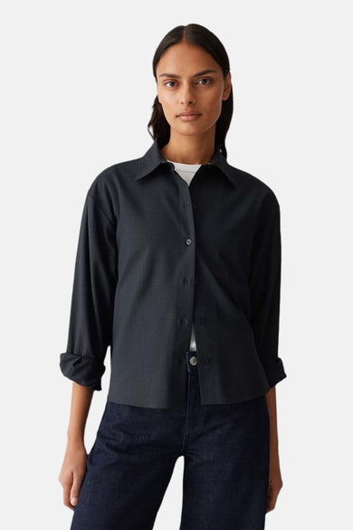 Chemise bleue à manches longues d'OPUS, vue de derrière, avec un short en jean foncé et des chaussures marron.