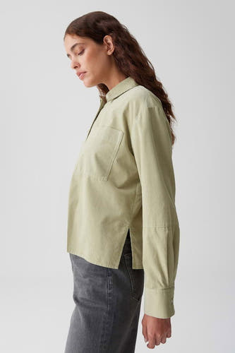 Blouse verte avec des manches longues d'OPUS, avec une poche poitr et et des poches latérales, portée avec des jeans gris, en vue de dos.