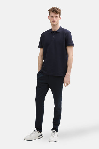 Donkerblauwe polo met korte mouwen van TOM TAILOR, gecombineerd met donkere broek en witte sneakers.