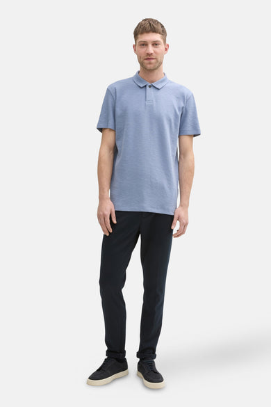 Polo bleu avec manches courtes de TOM TAILOR, avec une subtile texture et porté avec un pantalon foncé et des baskets.