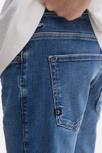 Jean bleu moyen droit de TOM TAILOR, avec étiquette de marque sur la poche arrière et des boutons décoratifs blancs.