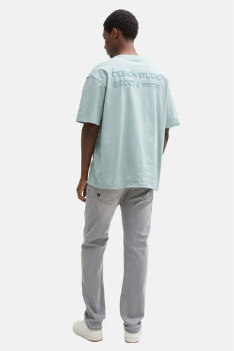 Jean slim gris de TOM TAILOR, avec une marque subtile sur la poche arrière et des baskets blanches.