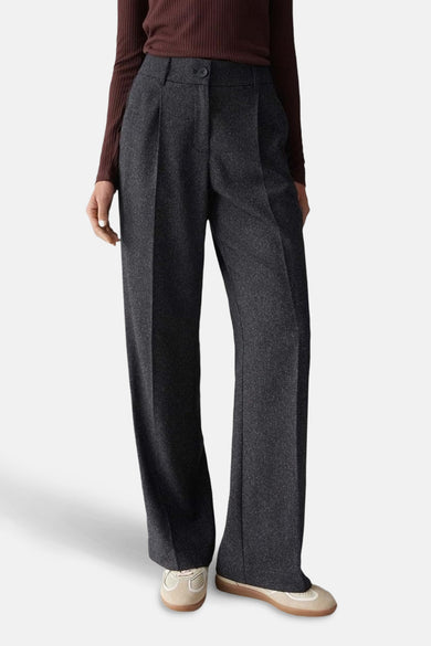 Pantalon noir d'OPUS avec des jambes larges et une fermeture à boutons, porté avec un haut marron et des chaussures beige.