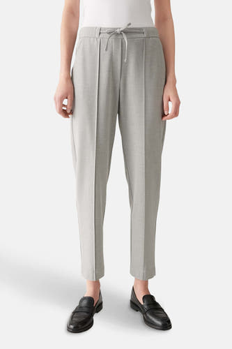 Pantalon gris OPUS, avec une fermeture éclair et porté avec des loafers noirs.