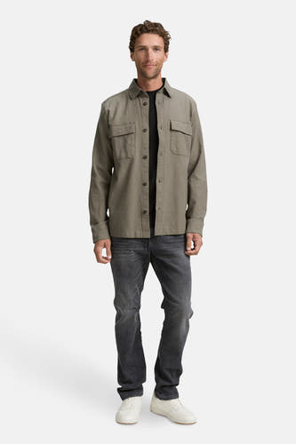 Chemise verte à manches longues de TOM TAILOR, avec des poches sur la poitrine, portée sur un t-shirt noir et des jeans gris.