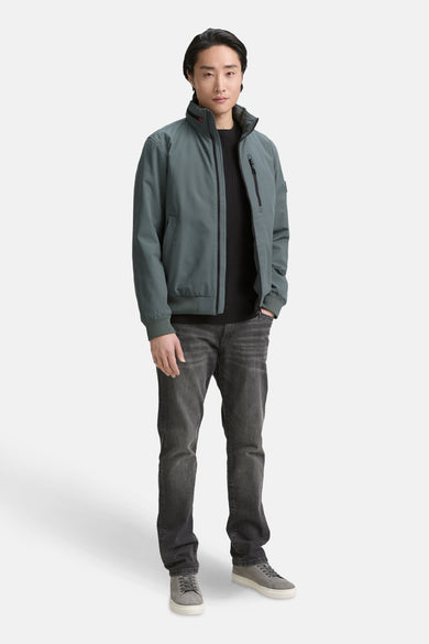 Manteau vert court de TOM TAILOR, avec un pull noir et des jeans gris et des chaussures.