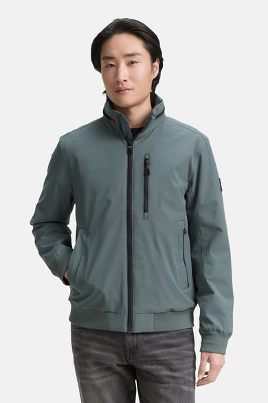Veste courte verte de TOM TAILOR, avec des manches longues et une fermeture éclair, portée avec des jeans foncés.