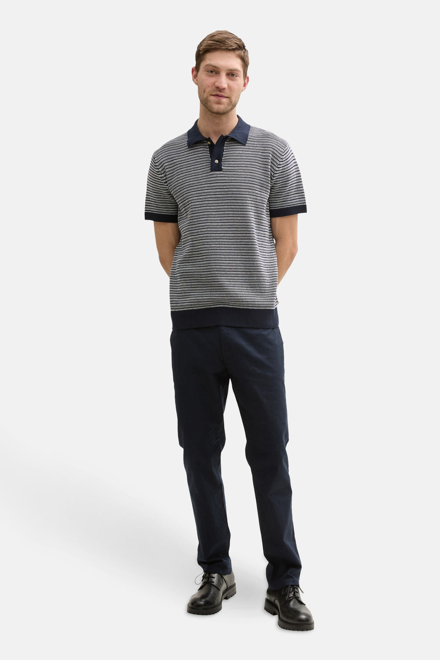 Blauwe polo van TOM TAILOR, met een fijn streepmotief en donkerblauwe broek en zwarte schoenen.
