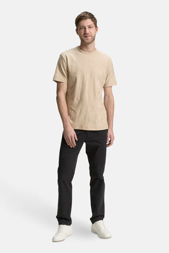 Beige T-shirt met korte mouwen van TOM TAILOR, met subtiele palmboomprint, gecombineerd met een zwarte broek en witte sneakers.
