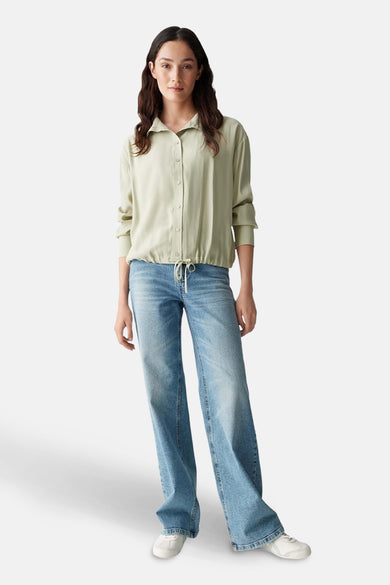 T-shirt vert de OPUS long manches, avec une corde à l'extrémité inférieure, porté avec un jean.