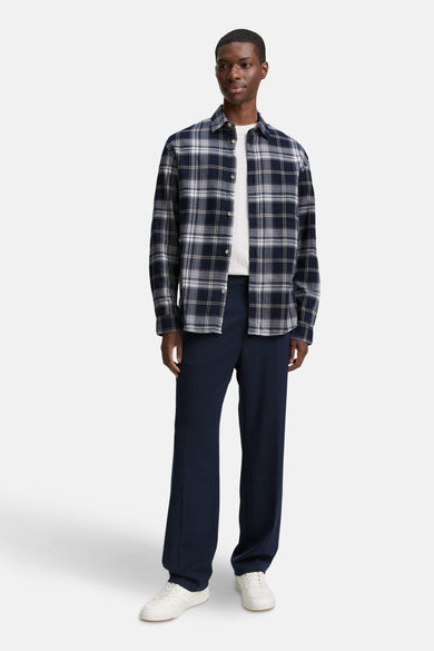 Chemise bleue à manches longues de TOM TAILOR, avec un motif à carreaux, portée sur un t-shirt blanc et des pantalons bleu marine et des baskets blanches.