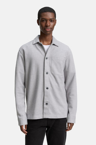 Chemise grise de TOM TAILOR, avec des manches longues et une poche poitrine port portée sur un un-shirt blanc.