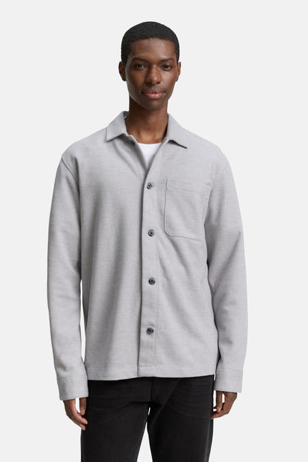 Chemise grise de TOM TAILOR, avec des manches longues et une poche poitrine port portée sur un un-shirt blanc.