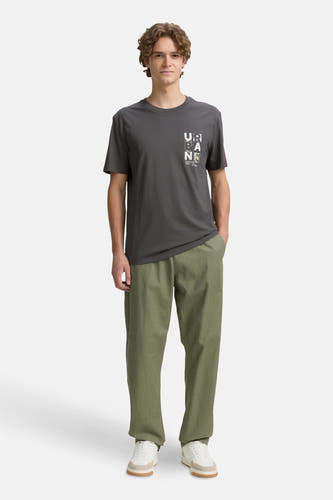 T-shirt gris à manches courtes de TOM TAILOR, avec une impression sur la poitrine, associé à des pantalons olive et des baskets blanches.