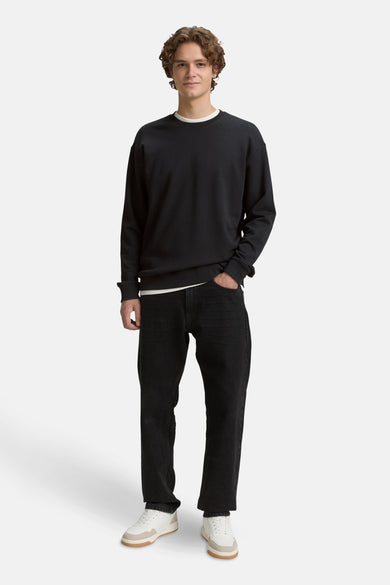 Pull noir de TOM TAILOR, avec des manches longues, associé à un t-shirt blanc et des jeans noirs.