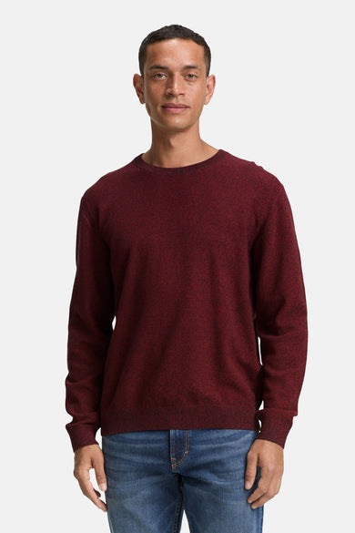 Pull rouge à col rond de Tom Tailor, avec une subtile texture et associé à des jeans bleus.