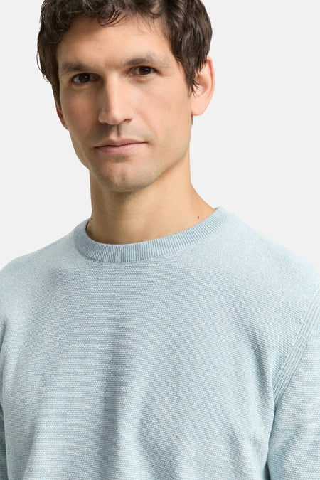 Mannelijk model draagt lichtblauwe trui.