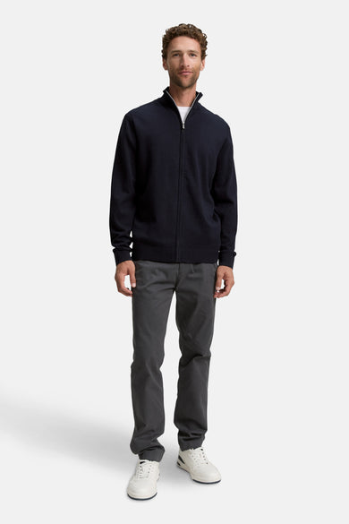 Gilet bleu de TOM TAILOR, porté sur un t-shirt blanc avec un pantalon gris et des baskets blanches.