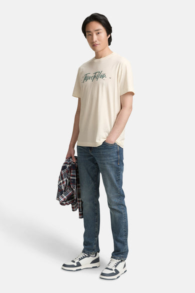 T-shirt blanc à manches courtes de TOM TAILOR, avec un slogan, associé à des jeans bleus et des baskets blanches.