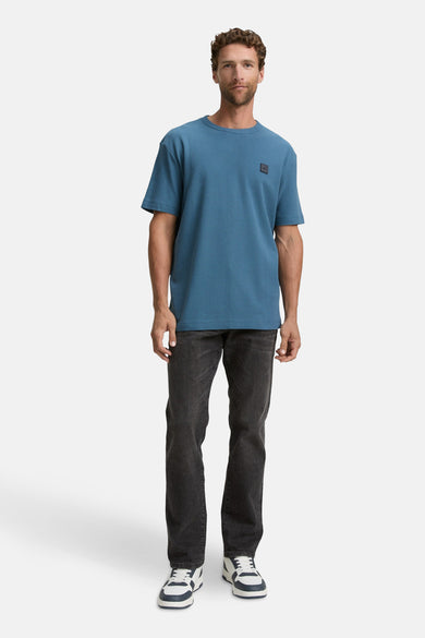 T-shirt bleu à manches courtes de TOM TAILOR, porté avec des jeans noirs et des baskets blanches.